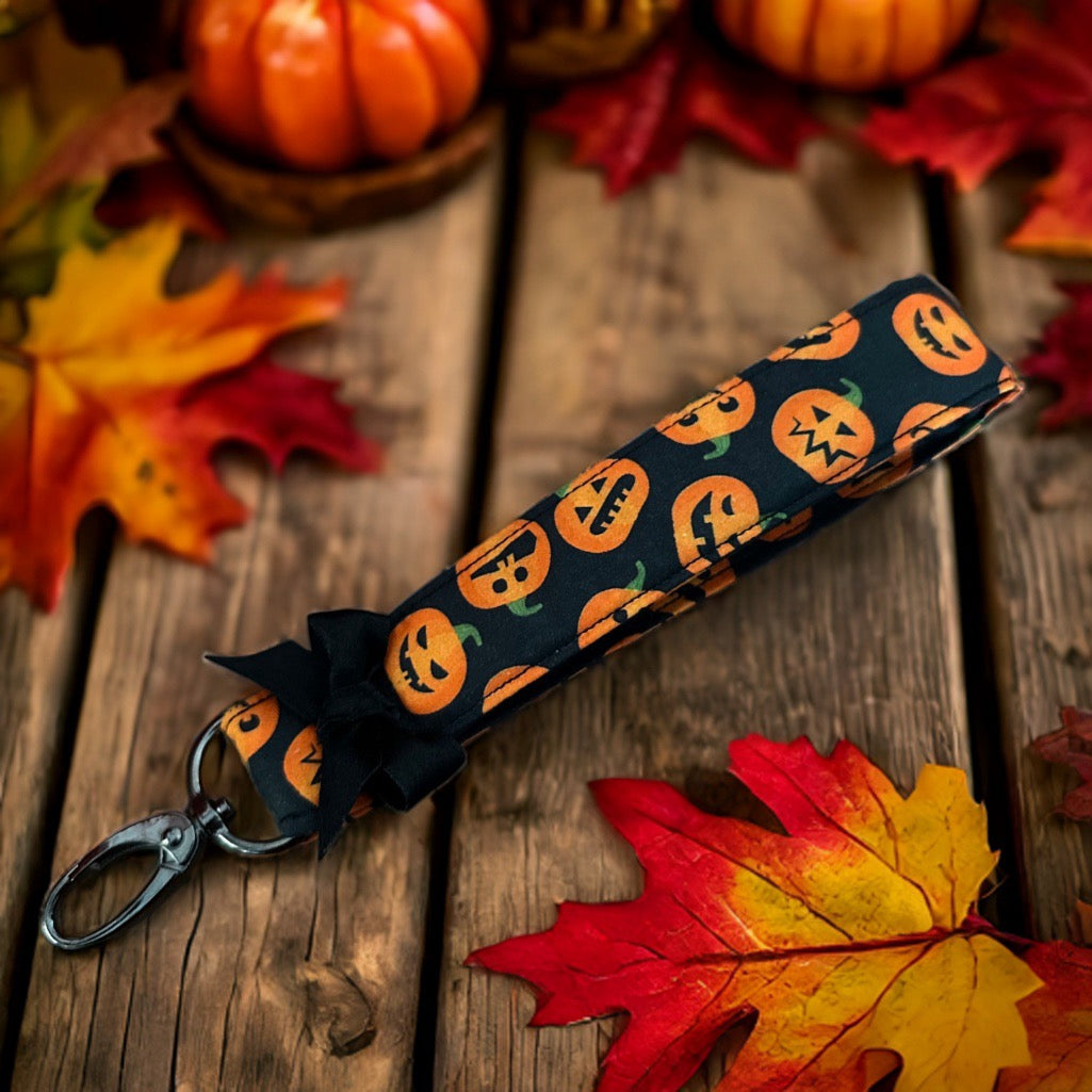 Schlüsselband mit orangen Kürbissen auf schwarzem Grund, einer schwarzen Schleife und einem schwarzen Karabiner