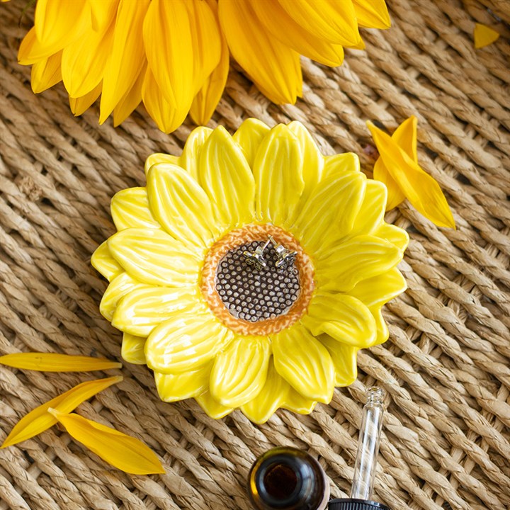 Keramik-Schmuckschale in Form einer Sonnenblume auf Bastunterlage mit gelben Blütenblättern und Schmuckstücken
