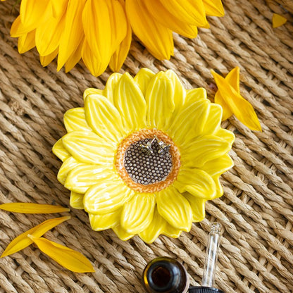 Keramik-Schmuckschale in Form einer Sonnenblume auf Bastunterlage mit gelben Blütenblättern und Schmuckstücken